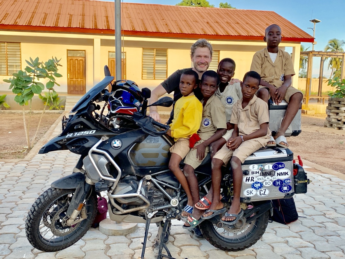 Eine Gruppe mit Kindern auf und neben dem Reisemotorrad.